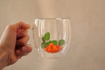 Person holds a glass of buckthorn tea with mint. Healthy drink against viruses