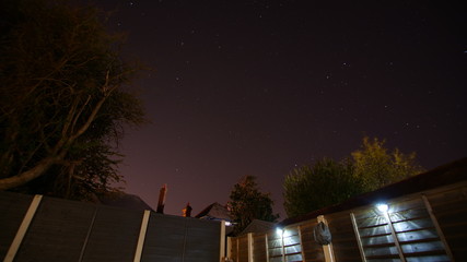 Clear sky at night, showing the fascinating stars, shot from a suburban garden, slightly purple red like light pollution