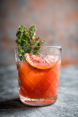 Old-0fashioned cocktail with blood oranges and thyme on the rustic background. Selective focus. Shallow depth of field.