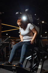 Fototapeta na wymiar overweight girl in sportswear training on fitness machine in gym