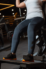 cropped view of overweight girl training on fitness machine