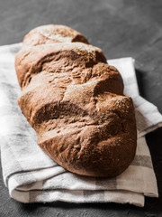 Loaf dark buckwheat bread on white textile napkin black table background. Fresh delicious homemade healthy bake. Bakery