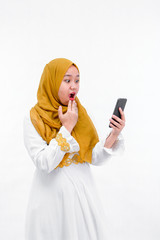 portrait of attractive asian muslim woman on white dress with hijab using a smartphone and look surprise isolated over white background