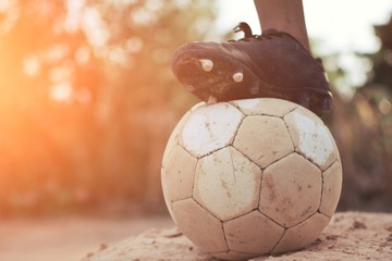 the boy's legs playing football on ground with fun in vintage style. Concept for young activity...