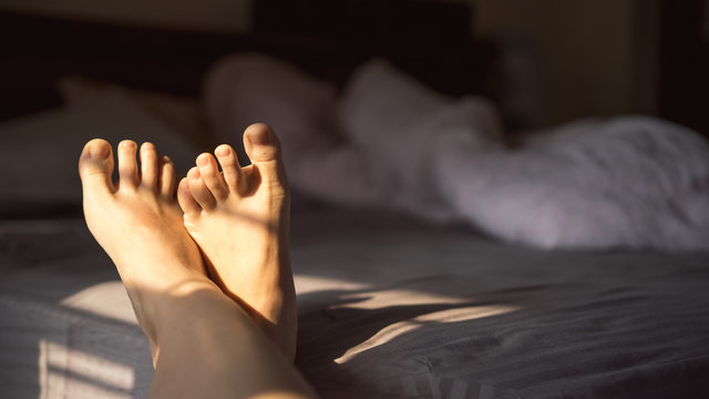 Close up photo of female feet on the bed in the morning, awakening, skip therapy, cropped image, Woman Body Legs Step Foot Sleep Relax Concept