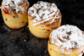 cruffins, The modern baking trend of the year is puffmuffin, a mix of croissants and cupcakes. On a black background sprinkled with powdered sugar