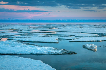 Ice drift on lake Baikal near the source of the Angara river at sunset