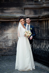 Wedding in a beautiful location. Wedding couple,bride and groom holding hands and going up the stairs of the castle. Elegant wedding dress with a long train