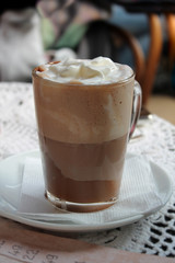 Coffee with milk, cream and foam in a glass cup