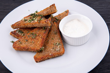 Garlic grens made of black bread, served with greens and cream sauce