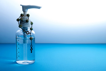 Coronavirus prevention , Bottle of hand sanitizer alcohol gel With a Wood rosary - Blue background 1