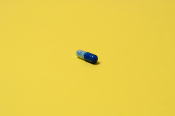 Blue pill on a yellow background, isolate, with place for text