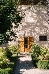 Old wooden door open and the facade of the Medici Villa of Lilliano Wine Estate, Tuscany, Italy under the shade of trees.