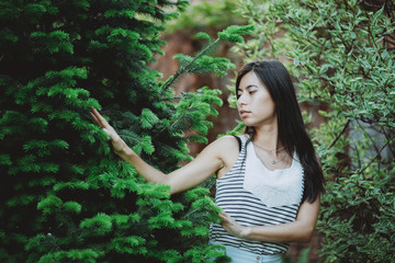 Gentle inspired girl caresses fir needles in garden in spring time. Young country girl with black...