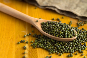 Healthy lifestyle. green mung beans in spoon with sackcloth on a yellow background. wooden spoon with dried mung bean and burlap on a wooden table. copy space.