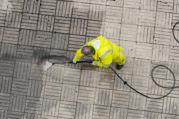 Worker cleaning a sidewalk with pressurized water. City Cleaning or maintenance concept. Top view