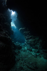 Light seeps into a dark, underwater cavern in the tropical Pacific Ocean. Caves and caverns riddle coral reefs and limestone islands.