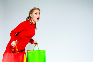 Shopping Ideas and Concepts. Portrait of Surprised Caucasian Girl  Posing With Plenty of Colorful Shopping Bags Against White Background.