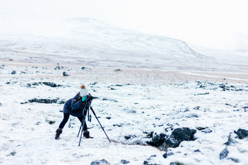 Fototapeta na wymiar Fotógrafa en la nieve con cámara y trípode