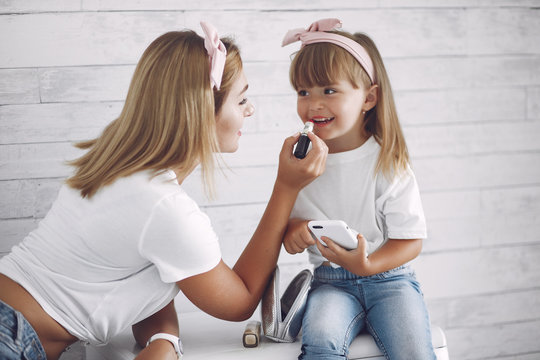 Beautiful woman with child. Woman in a white t-shirt. Little daughter in a bathroom