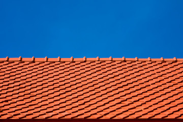 Low angle view of red tiles roof slope in horizontal pattern against blue clear sky  in sunny day, exterior architecture concept 
