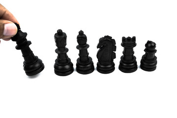 Different black color pawns placed in order of their size and the king is falling before a white background