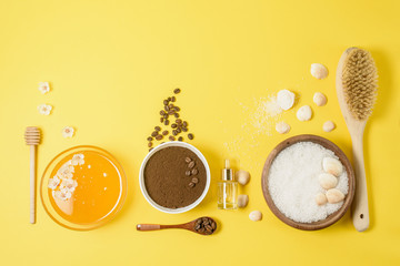 natural organic ingredients-sea salt, coffee scrub, honey and a hard body brush on a yellow background. home skin care for cellulite. concept of skin care, home Spa. the view from the top