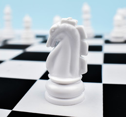 White knight placed on top of a white square of the chess board in a game