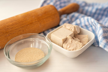 dried and fresh yeast on a white kitchen bacground with wooden rolling pin