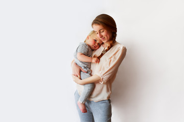 Pretty beautiful young mother holding in her arms. . maternity content. child 1 year old boy or girl. long red hair, light home wear