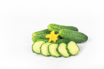 Group of fresh green pickling cucumbers with slices and yellow flower on white background