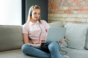 attractive freelancer in headset using laptop in living room