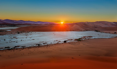 Fototapeta na wymiar The sunrise above sand dunes in the Namibian Desert near Sossusvlei in Namibia.