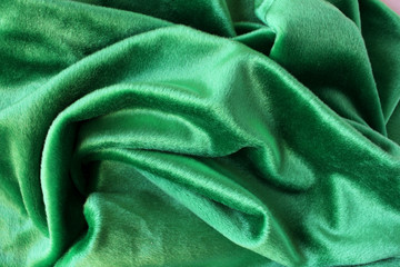 Green velour fabric texture. Wavy folds background. Fragment of a drapery dark green cloth material
