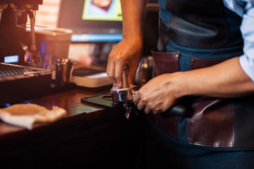 Barista holding portafilter and coffee tamper making  coffee at cafe.
