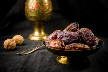 Big luxury dried date fruit in bowls on the dark surface, kurma ramadan kareem concept, close up.