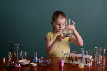 girl in safety glasses at home doing experiments with chemicals. school experiments at home.