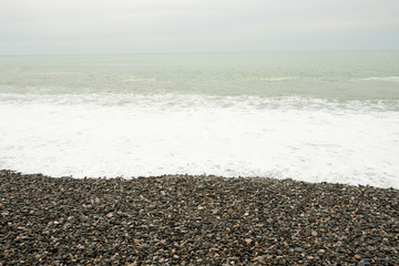 Waves on the beach shore. Shore of rocky pebbles. Mainly cloudy. Day, spring, Georgia.