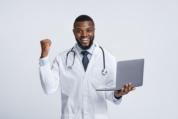 Black doctor with laptop exclaiming happiness over white