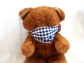 Teddybär trägt selbstgemachte Mund-Nasen-Alltagsmaske in der Corona-Krise
