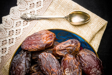 Big luxury dried date fruit in bowls on the dark surface, kurma ramadan kareem concept, close up.
