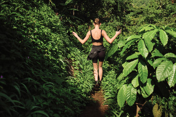Naklejka na ściany i meble Back view of attractive girl exploring wild jungle on tropical island