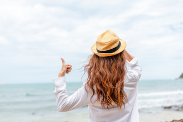 Fototapeta na wymiar smiling young woman in sun hat and finger thumb up on beach. summer, holidays, vacation, travel concept