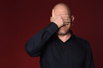 man cover his face on red background