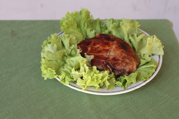Juicy pork steak grilled on a plate on a fresh green salad