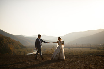 Wedding photo session of the bride and groom in the mountains. Photoshoot at sunset.