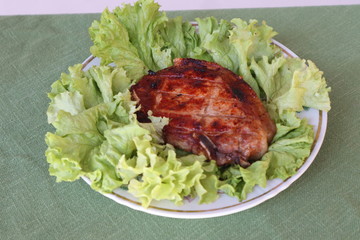 Juicy pork steak grilled on a plate on a fresh green salad