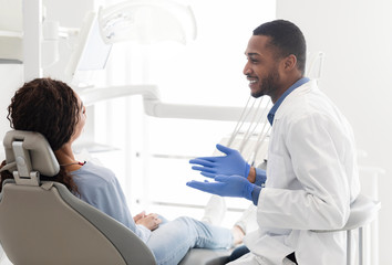 Friendly black dentist explaining patient treatment plan