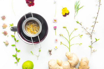 chamomile tea in clay cup, herbal flowers and leaf, ginger and lime