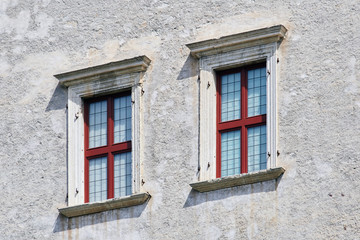 Fototapeta na wymiar Two Italian windows on the old castle wall facade with wooden red color frame